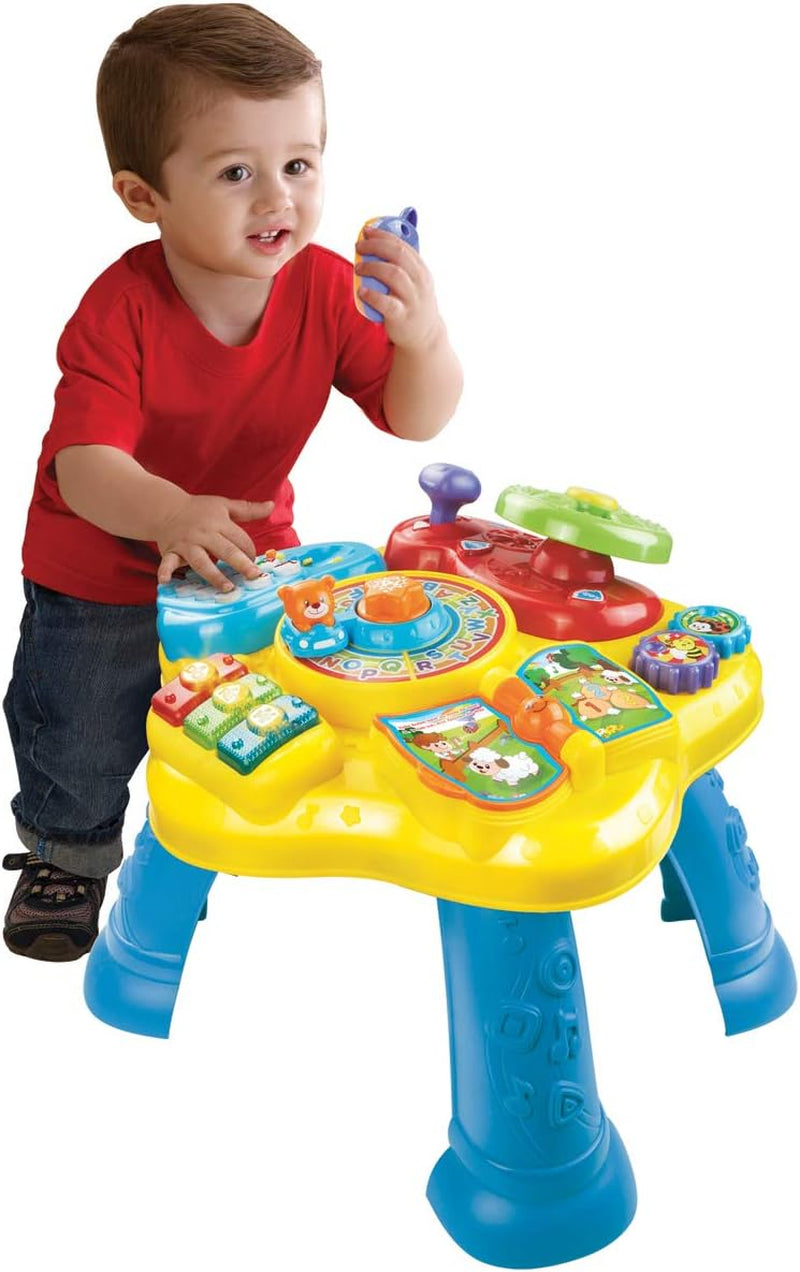 VTech Baby Adventure Play Table - Masă de joacă colorată pentru bebeluși cu 6 câmpuri de joc și elemente interactive & Baby My First Song Book Carte colorată cu 6 pagini și elemente mobile pentru joacă Jucarii Bebe Naty Shop